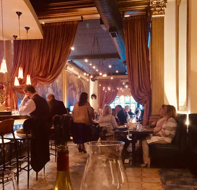 Warmly lit Sotto Sopra dining room framed by tall curtains